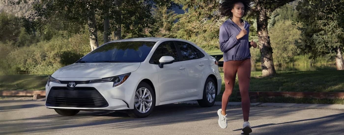 A white 2025 Toyota Corolla for sale near Brattleboro parked near a jogger.