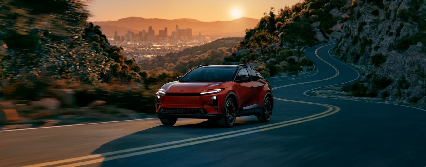 Orange 2026 Toyota CH-R driving on a winding highway