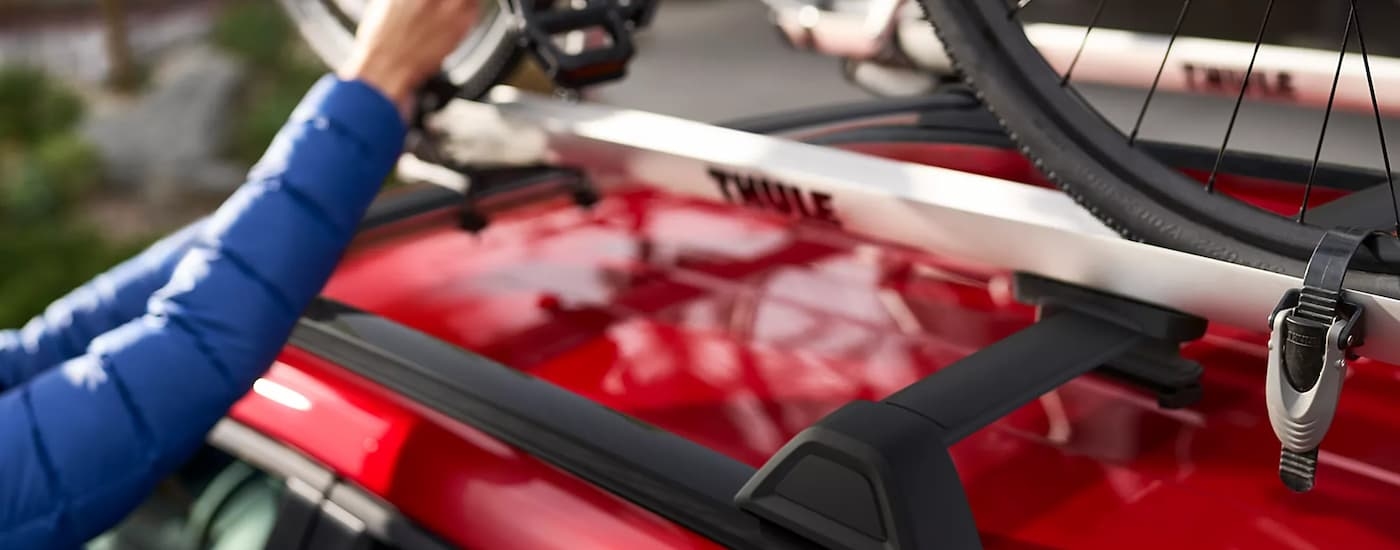 Bike being strapped to the roof racks on a red 2026 Subaru Solterra