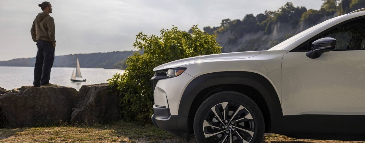 White 2025 Mazda CX-50 Hybrid parked near a sailboat