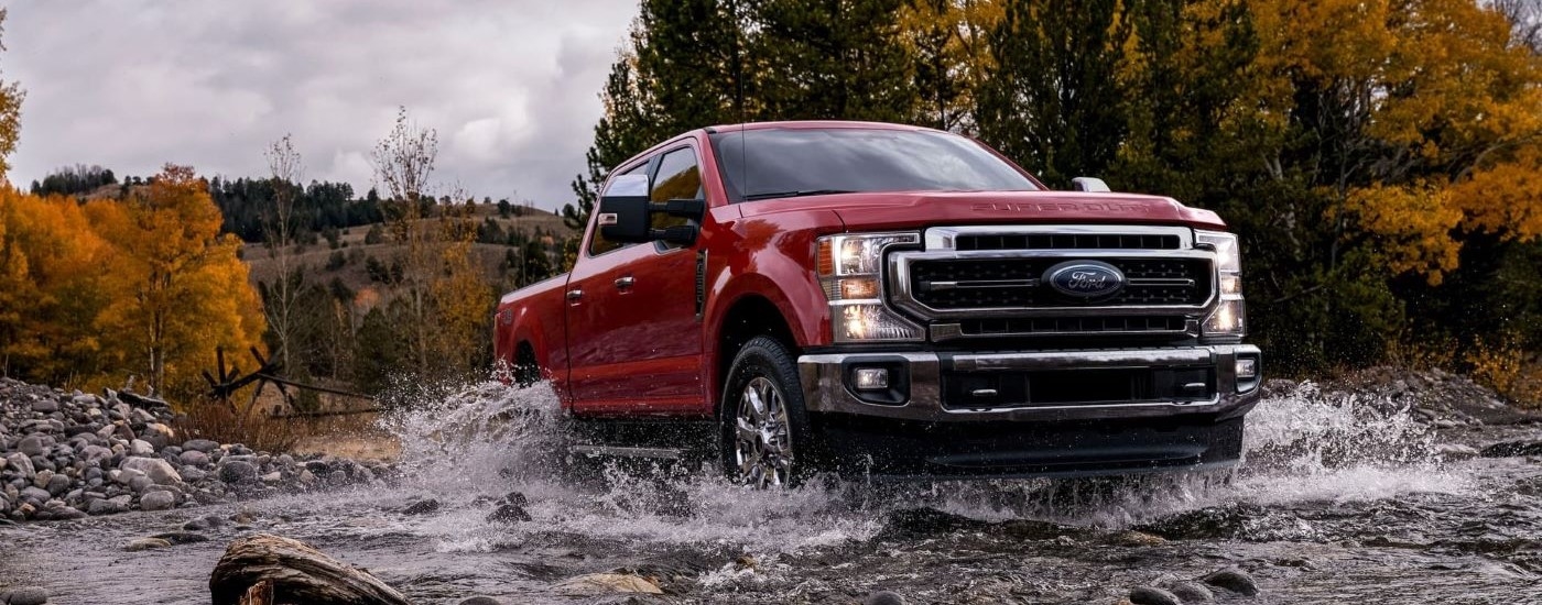 Red 2025 Ford F-250 for sale in Westminster driving over a shallow river.