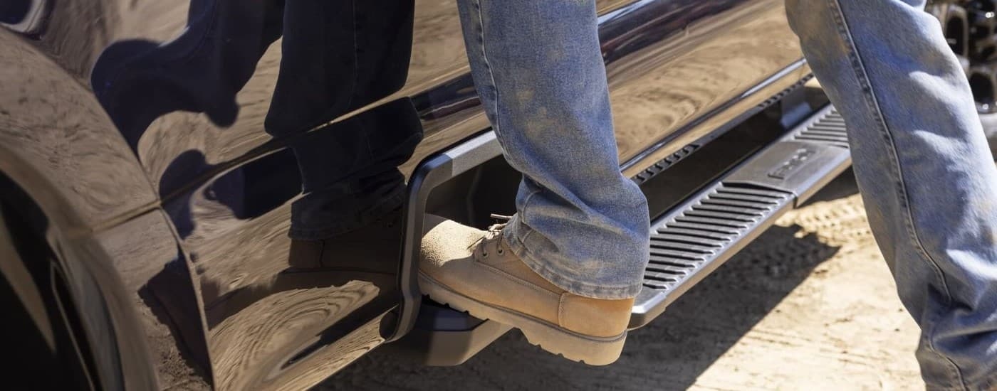 Close-up on a person using the door step on a black 2025 Ford F-250 for sale.