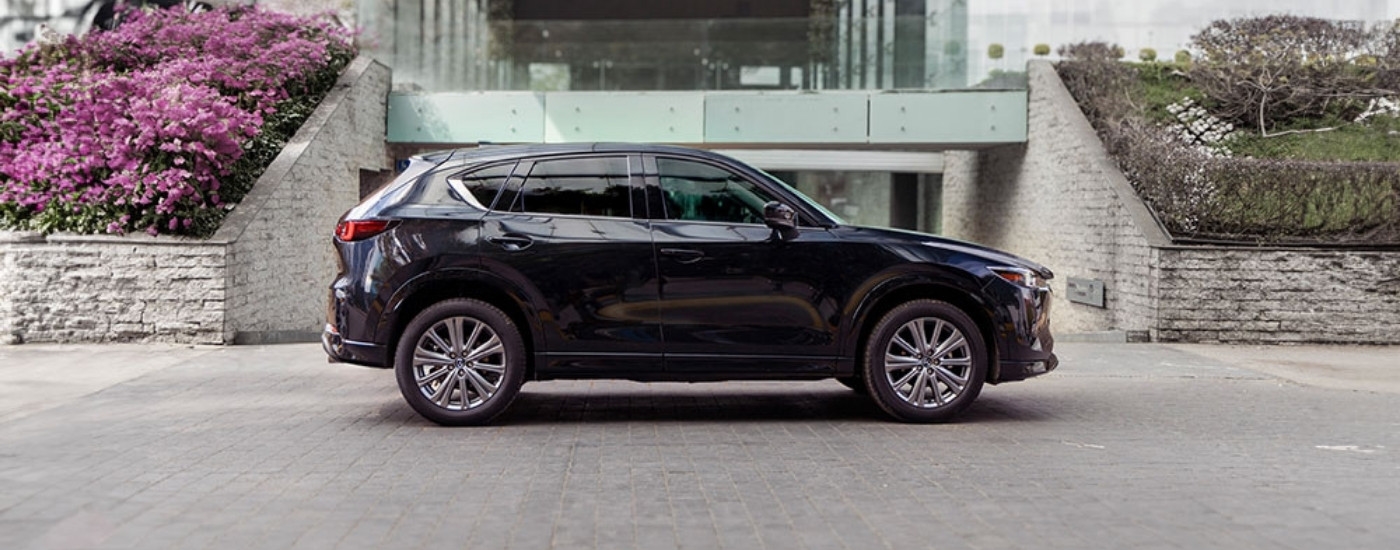 Dark blue 2025 Mazda CX-5 parked near a foot bridge