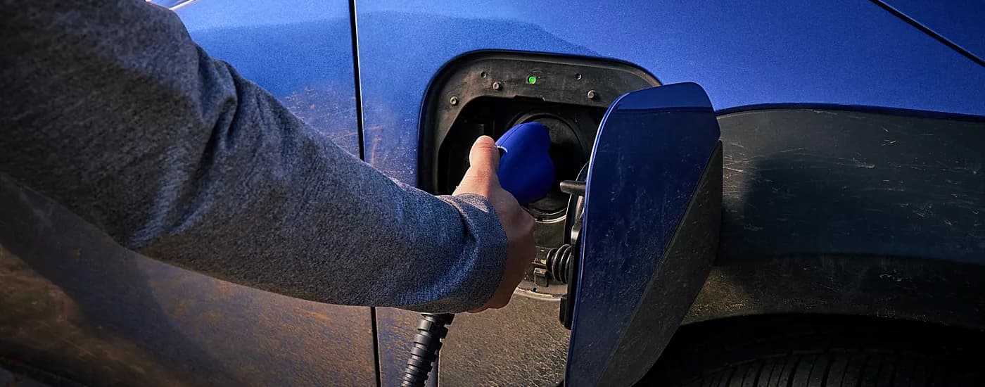 Person plugging an EV charger in a blue 2026 Subaru Trailseeker