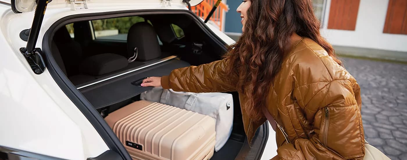 Woman putting luggage in the back of a white 2026 Subaru Impreza