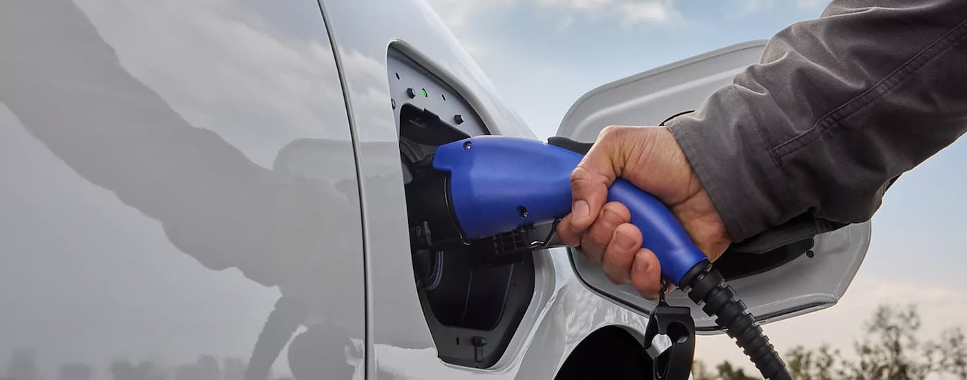 Hand plugging an EV charger into a white 2026 Subaru Solterra