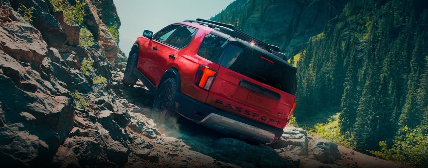 A red 2026 Honda Pilot TrailSport Elite off-roading.