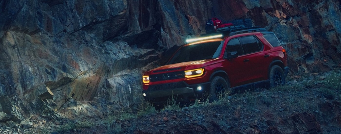 A red 2026 Honda Pilot TrailSport Elite driving at night.