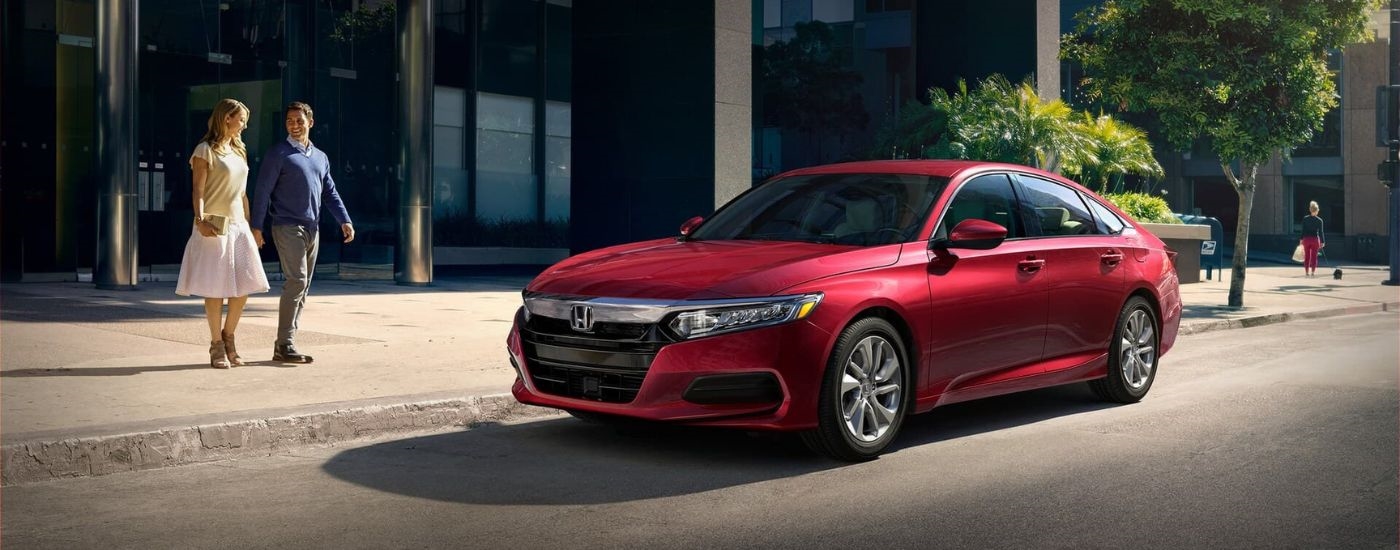 Red 2020 Honda Accord parked by a curb from a dealer with a used SUVs for sale.