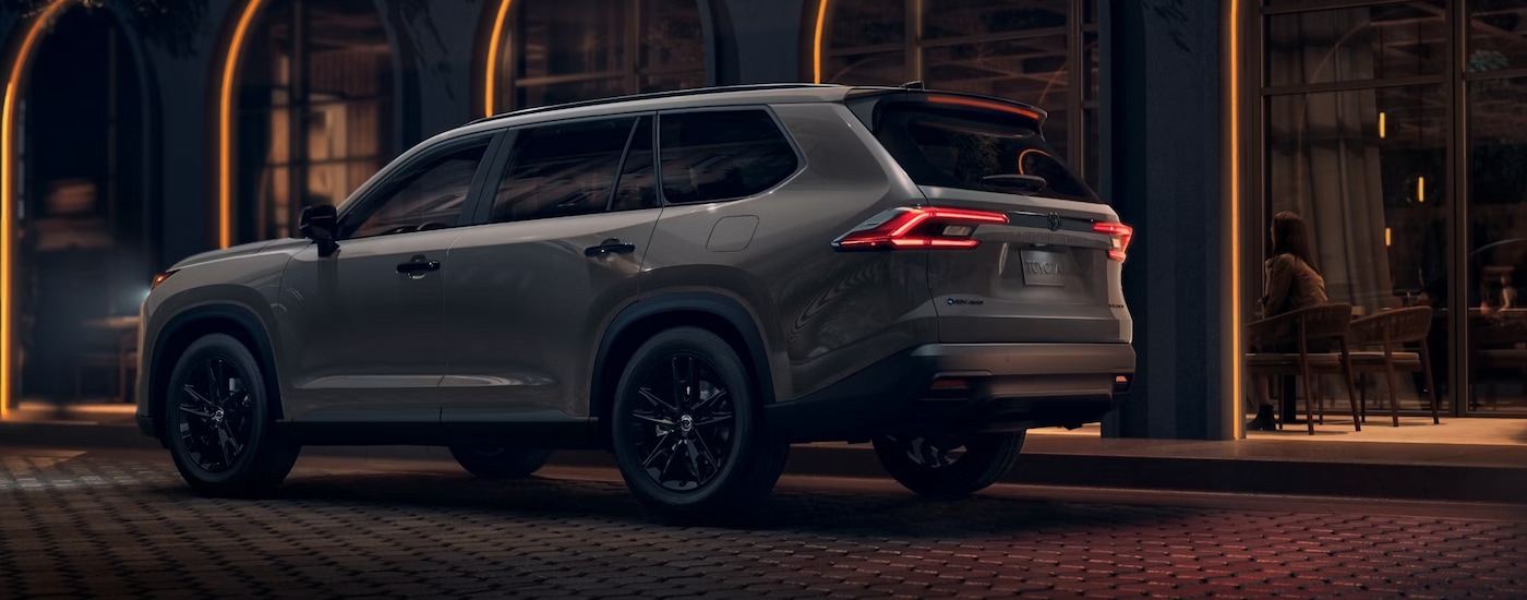 Rear of a grey 2025 Toyota Grand Highlander parked outside a building.