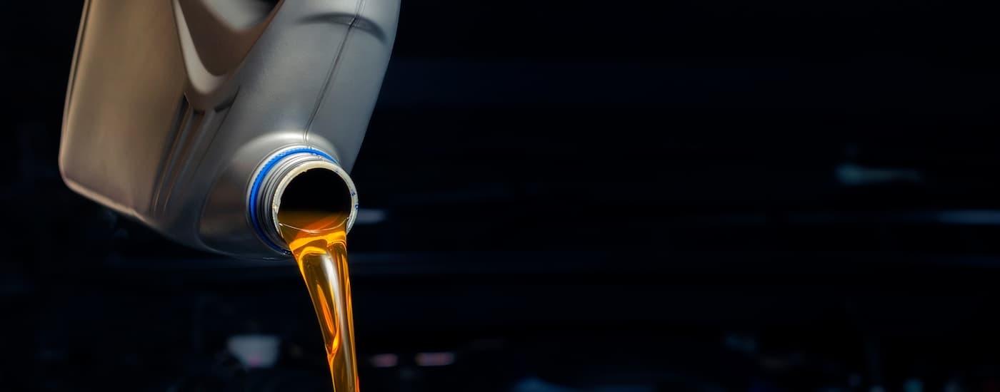 Oil pouring out of a grey bottle into an engine