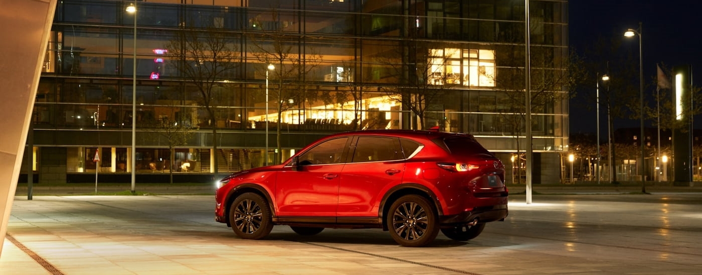 Rear of a red 2025 Mazda CX-5 parked outside of a building.