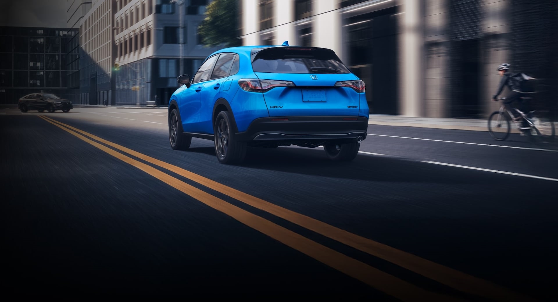 2026 Honda HR-V driving through a city with a bicyclist on the right