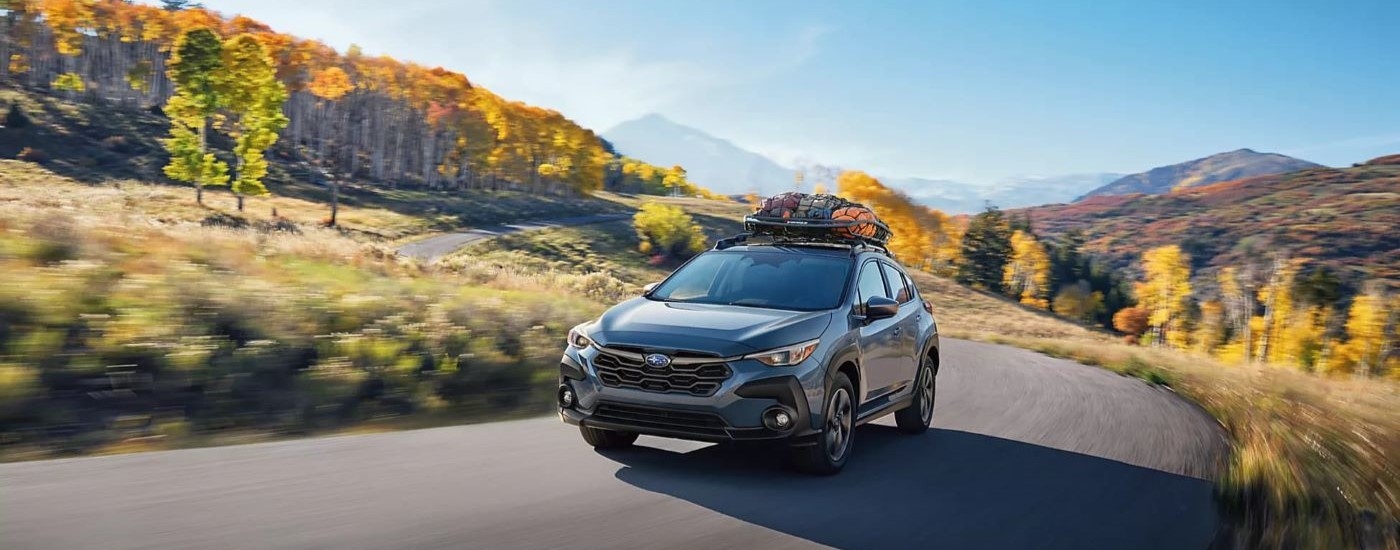 Grey 2026 Subaru Crosstrek Hybrid driving down a road.