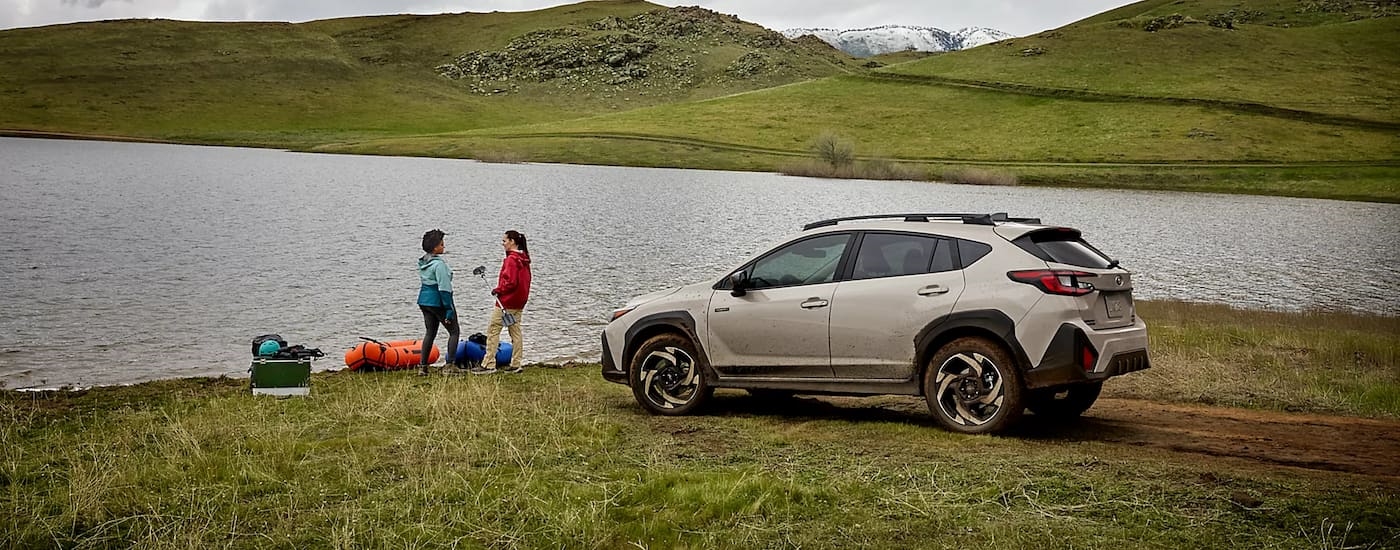 Rear of a tan 2026 Subaru Crosstrek Hybrid parked near a lake.