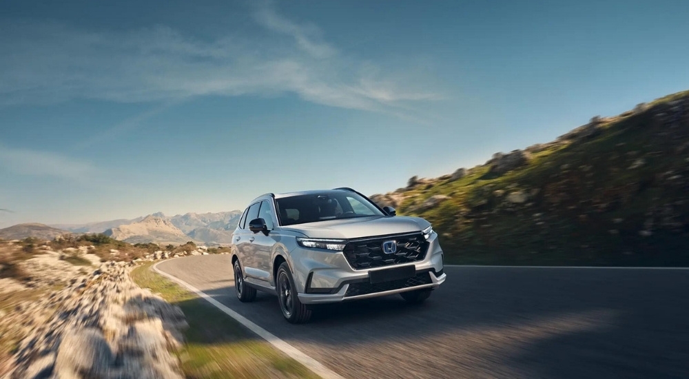 White 2026 Honda CR-V Hybrid for sale near Edmonds driving down a road.