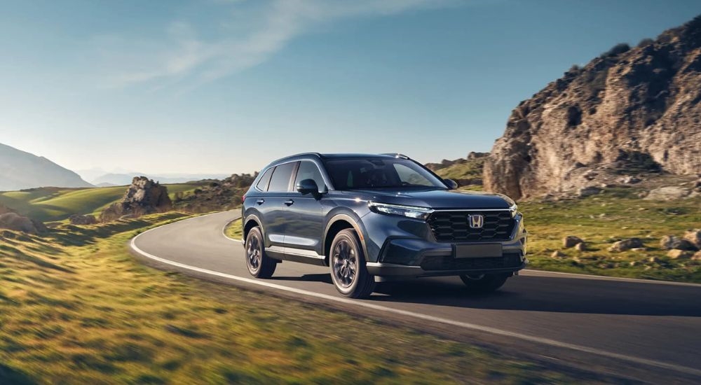 Blue 2026 Honda CR-V Hybrid driving around a bend.