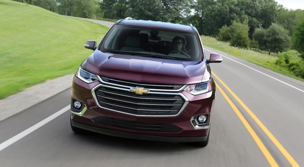 Red 2018 Chevy Traverse driving down a road.