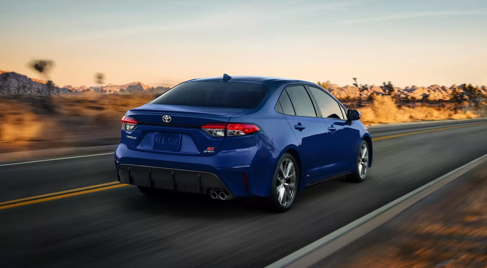Rear of a blue 2026 Toyota Corolla driving down an open road.