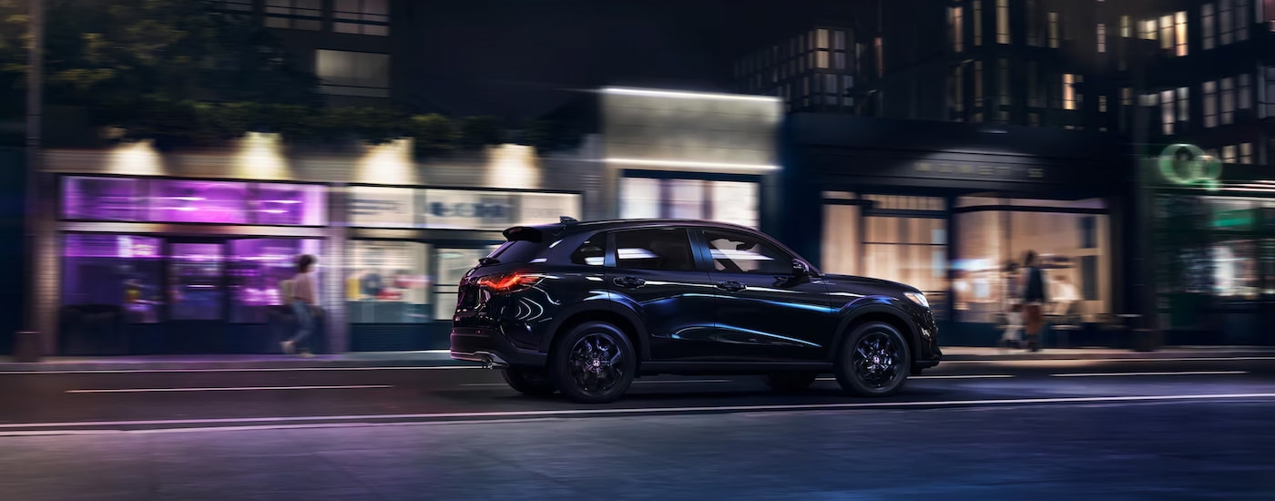Black 2026 Honda HR-V Sport driving on a city street at night