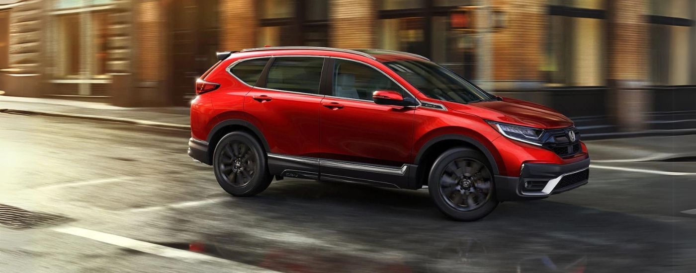 Red 2021 Honda CR-V driving on a city corner