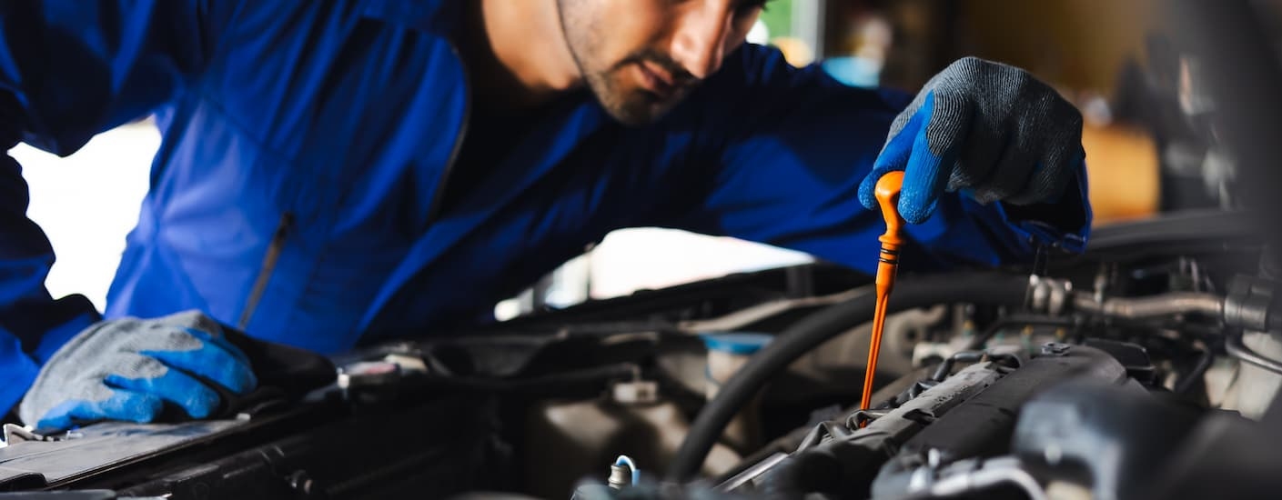 Mechanic checking the oil stick on a vehicle at a Honda service center near Elizabeth