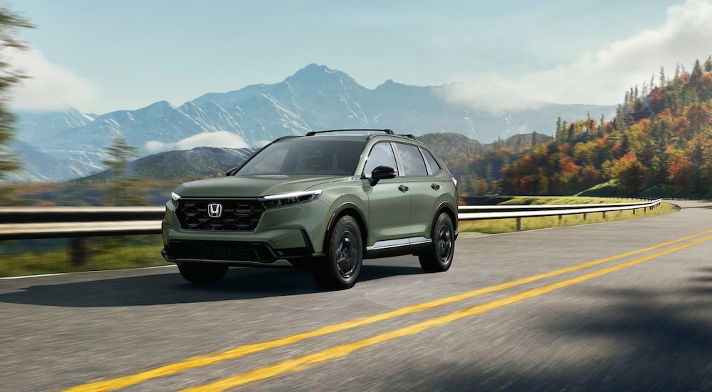 Green 2026 Honda CR-V driving down a road.