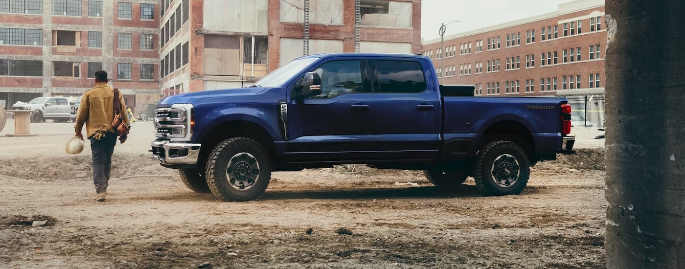 Side of a blue 2026 Ford F-350 parked off-road near a worksite.