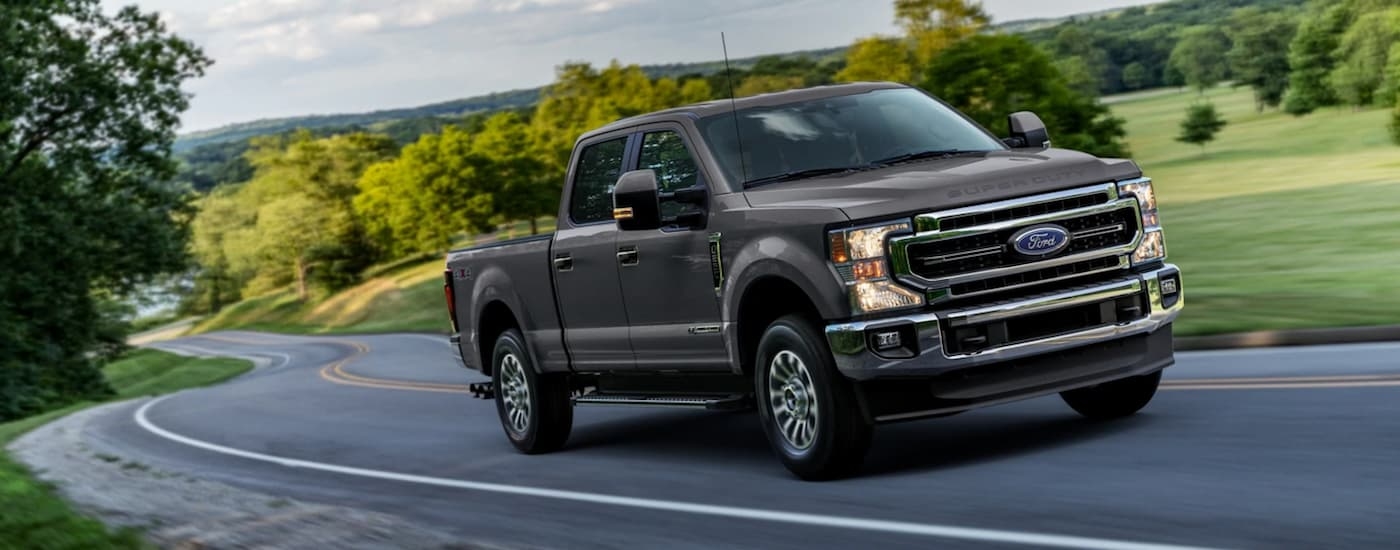 Grey 2021 Ford F-250 Super Duty driving on a winding road to a used car dealership