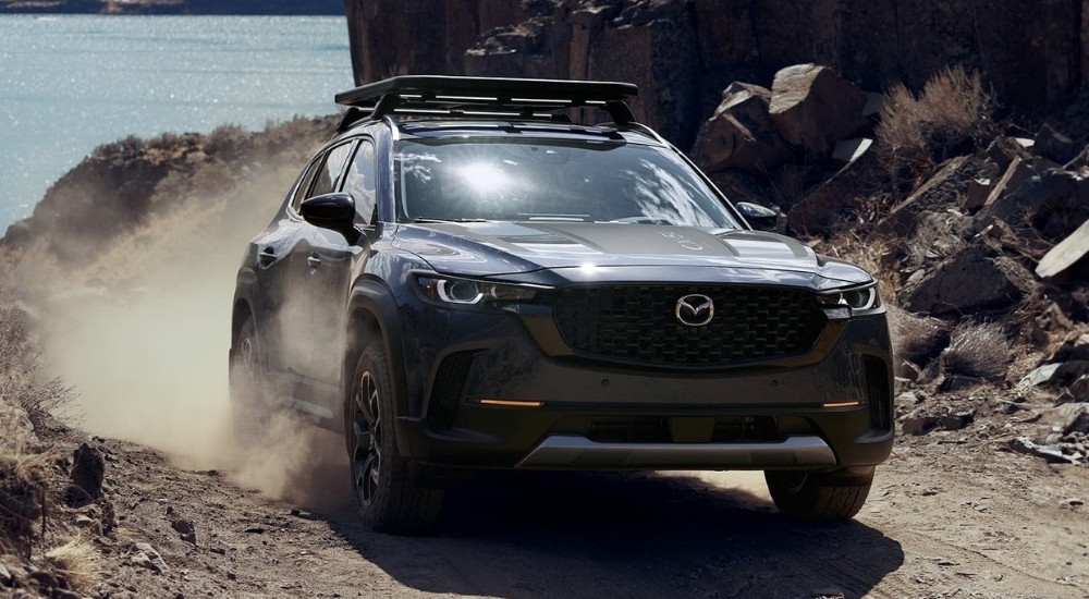 Blue 2025 Mazda CX-50 for sale driving near a lake