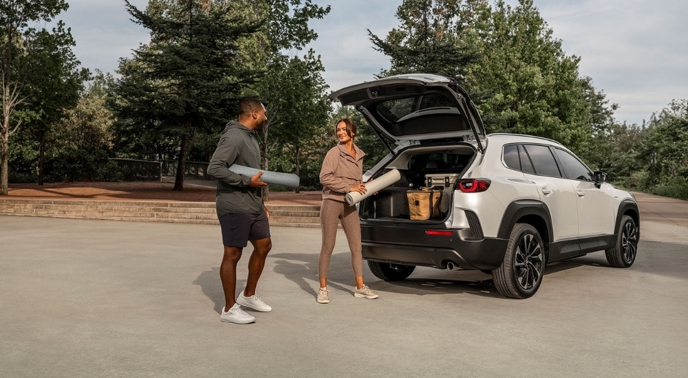 People with yoga mats near a white 2025 Mazda CX-50 Hybrid 