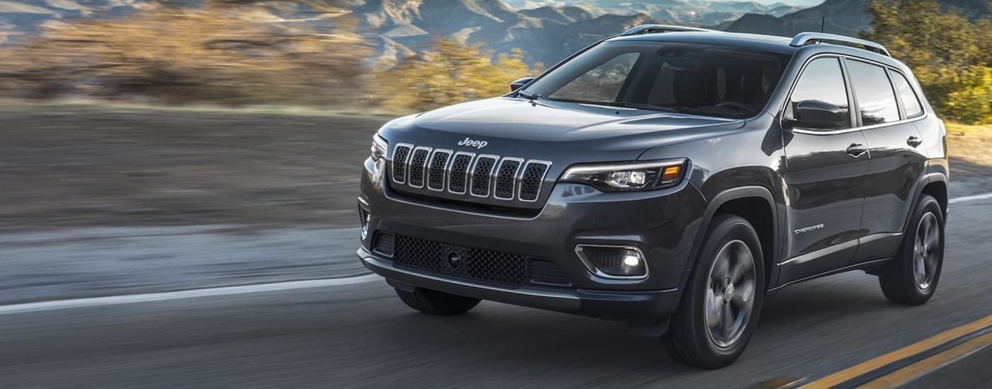 Black 2021 Jeep Cherokee driving down a down.