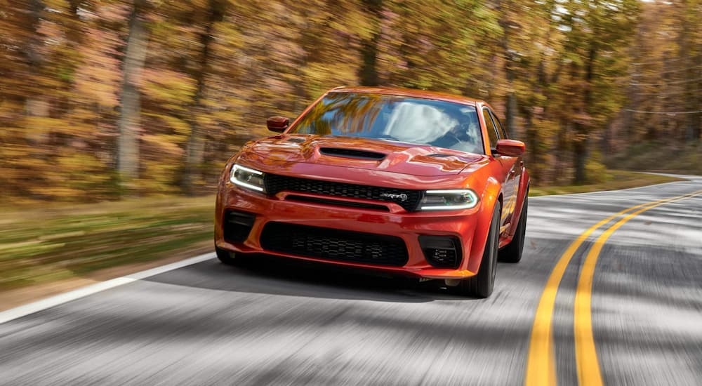 Orange 2022 Dodge Charger SRT Hellcat driving around a bend.