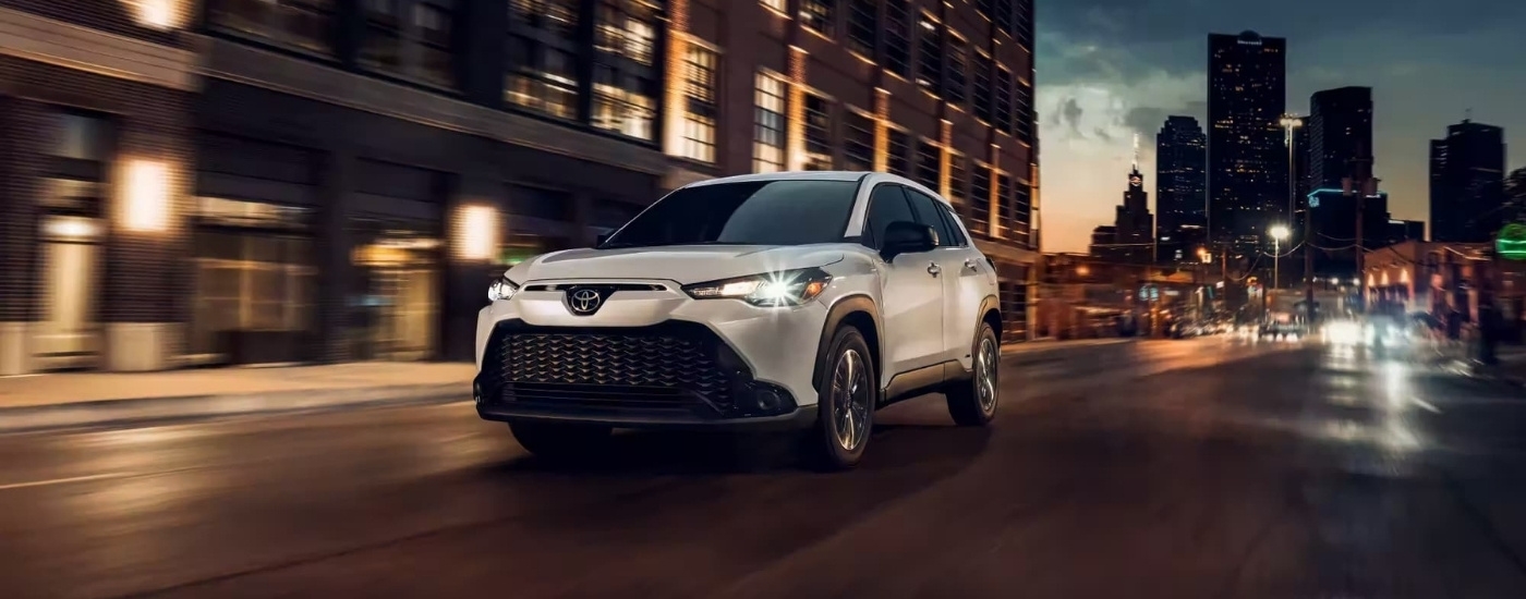 White 2023 Toyota Corolla Cross for sale near New Rochelle driving on a city street