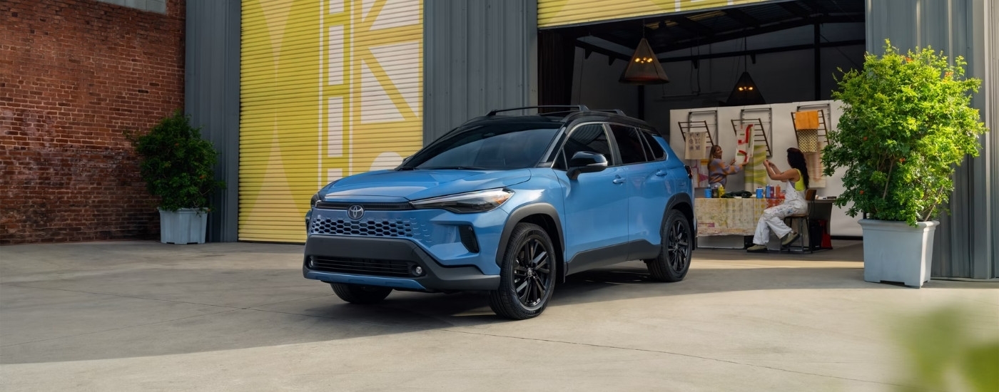 Blue 2026 Toyota Corolla Cross Hybrid XSE parked in front of rollup doors