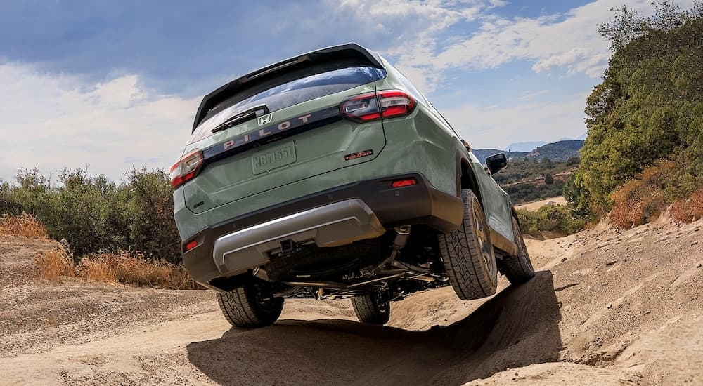 Green 2026 Honda Pilot Trailsport off-roading on a rocky trail