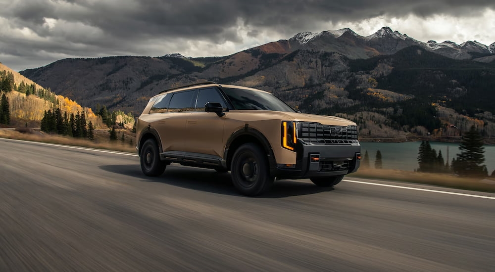 Brown 2027 Kia Telluride driving down a road from a Kia dealer near Katy.