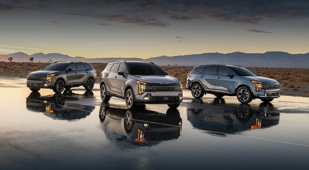 Three gray 2026 Kia Sportages parked on wet pavement
