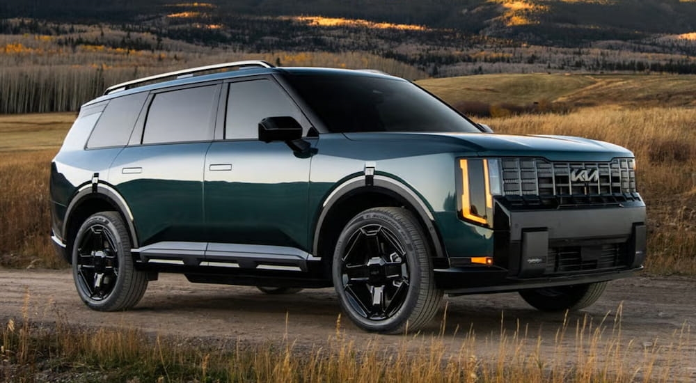 Dark green 2027 Kia Telluride driving down a road.