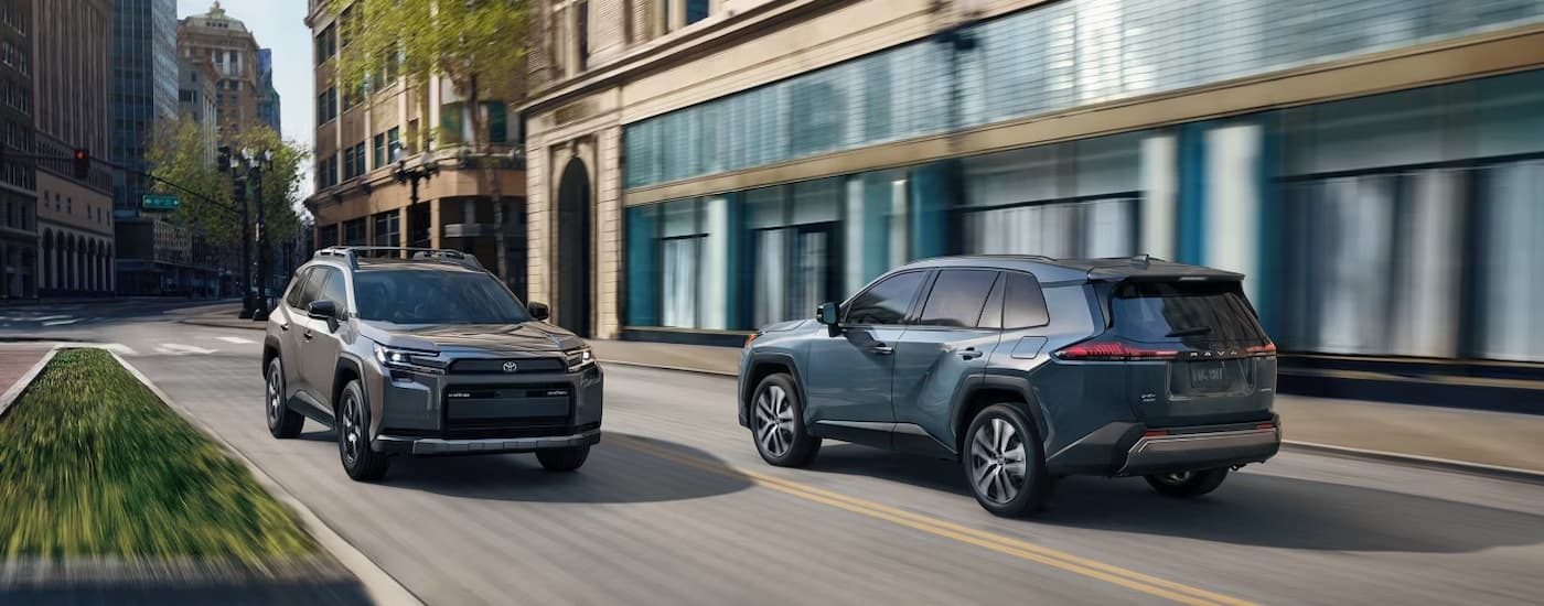 A grey and a blue 2026 Toyota RAV4 driving on a city street