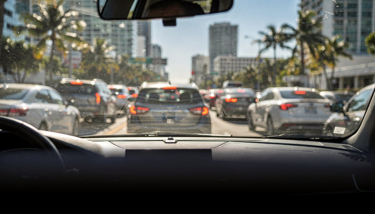 Driver's view of slow downtown Miami traffic through a windshield on a sunny day