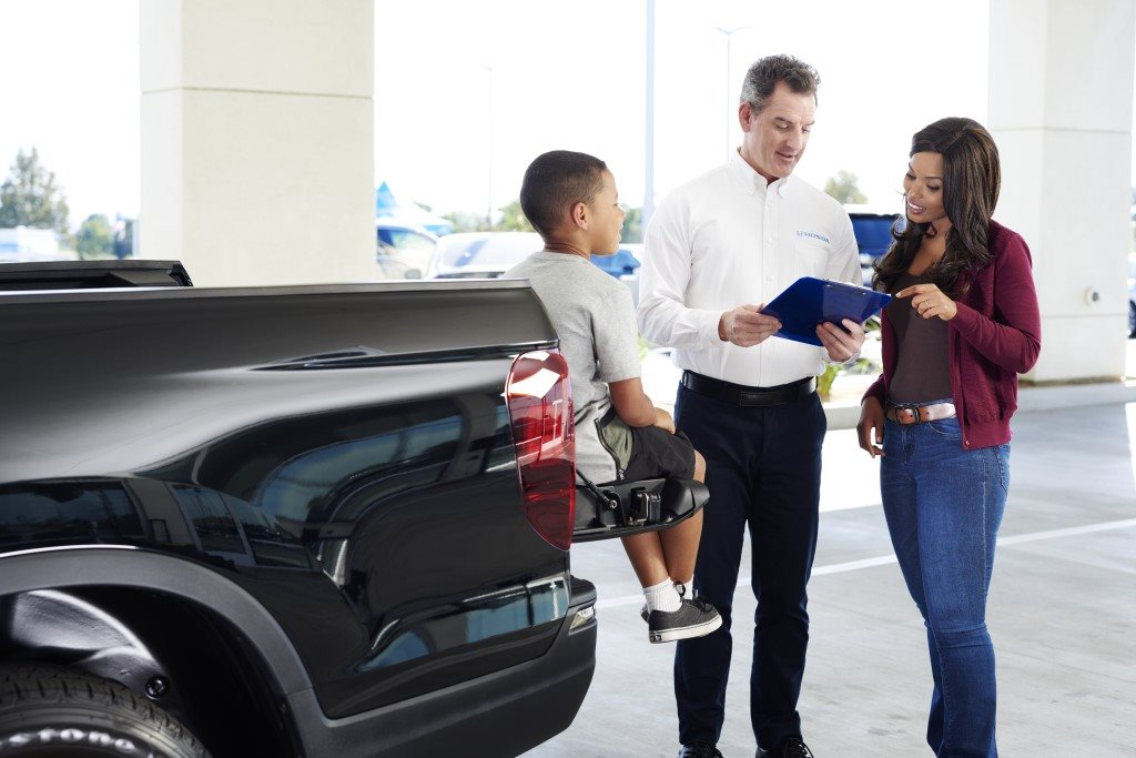 Honda team member reviewing paperwork with a customer beside a Honda Ridgeline