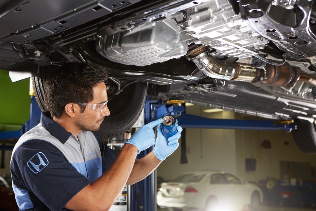 Honda technician inspecting a vehicle raised on a service lift