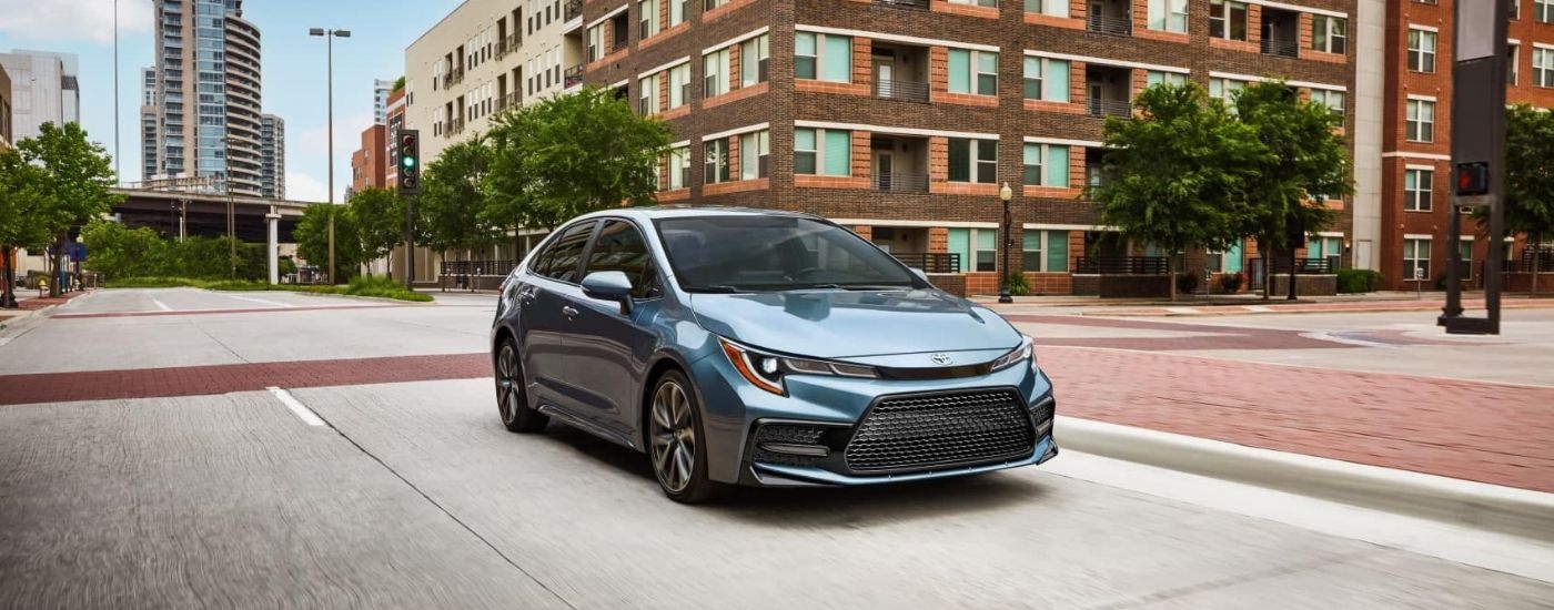 Blue 2022 Toyota Corolla XSE driving through an intersection from a used car dealership in Westminster.