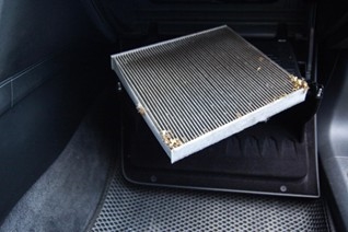 Technician replacing cabin air filter in vehicle