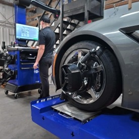 Vehicle undergoing wheel alignment inspection in service bay