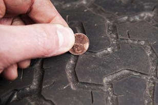 Technician checking tire tread depth using penny test
