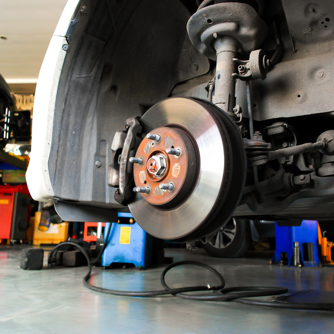 Vehicle brake and suspension components inspected on lift in service bay