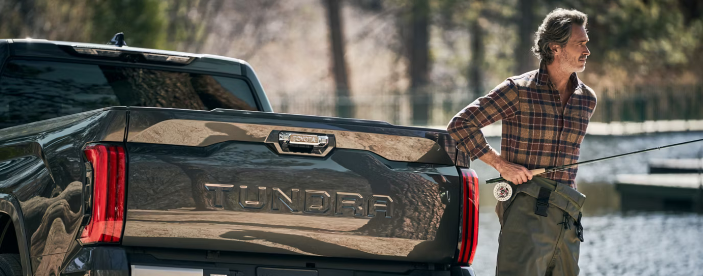 A person standing next to their black 2026 Toyota Tundra with a fishing rod
