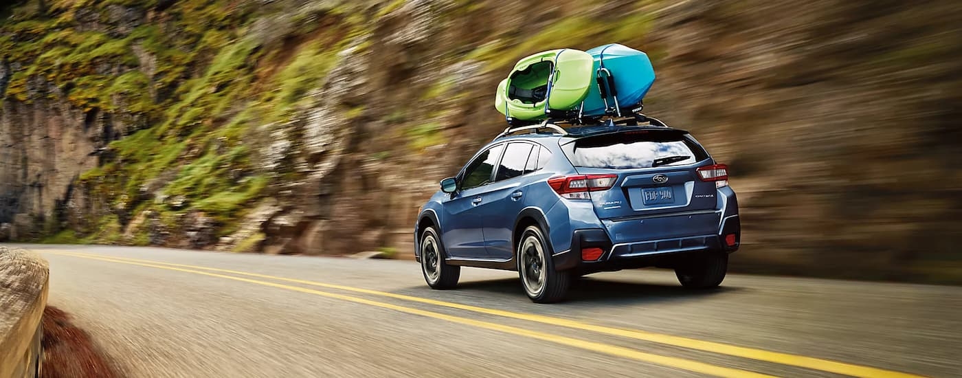 Rear of a dark blue 2022 Subaru Crosstrek driving down a road.